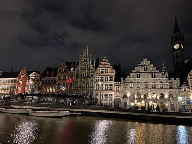 afbeelding van Gent in het donker, met verlichte historische gebouwen aan het water.