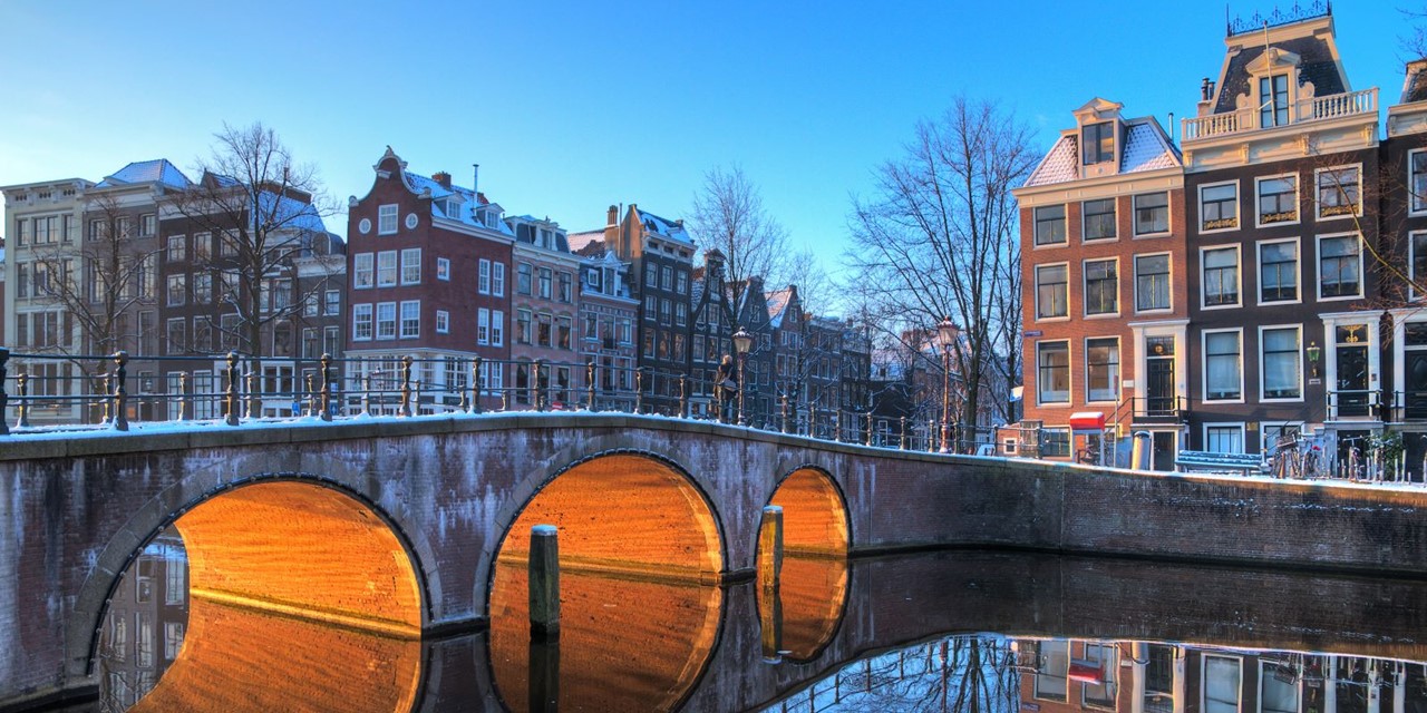 afbeelding van een Amsterdamse gracht in de schemering.