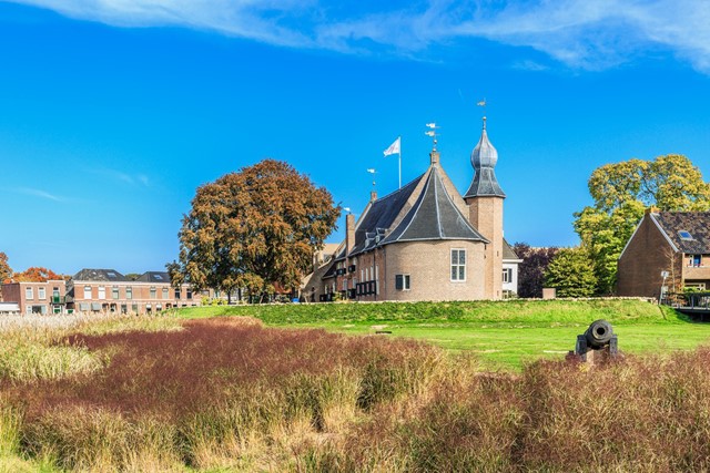 afbeelding van het oude vestingstadje Coevorden met een historisch pand en kanon in beeld.