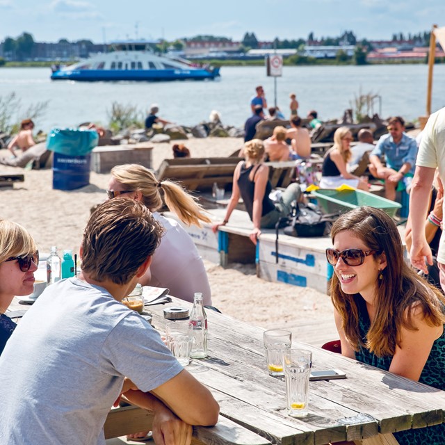 afbeelding van jonge mensen die een drankje drinken op het strandterras van Pllek.
