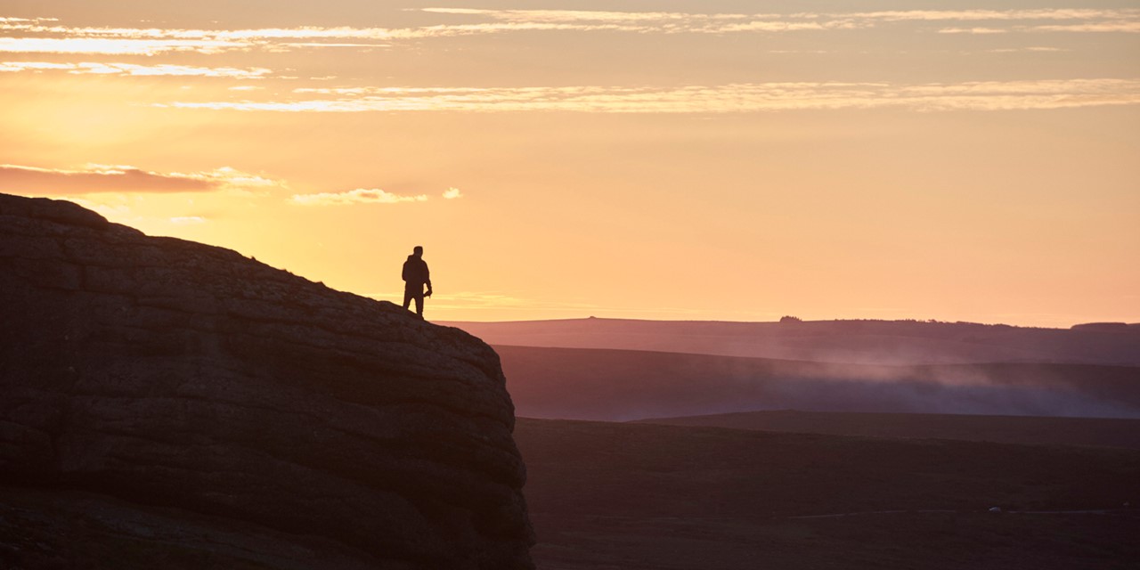 Hiker op de top van een Engelse berg met zonsondergang.
