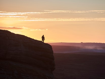 Hiker op de top van een Engelse berg met zonsondergang.