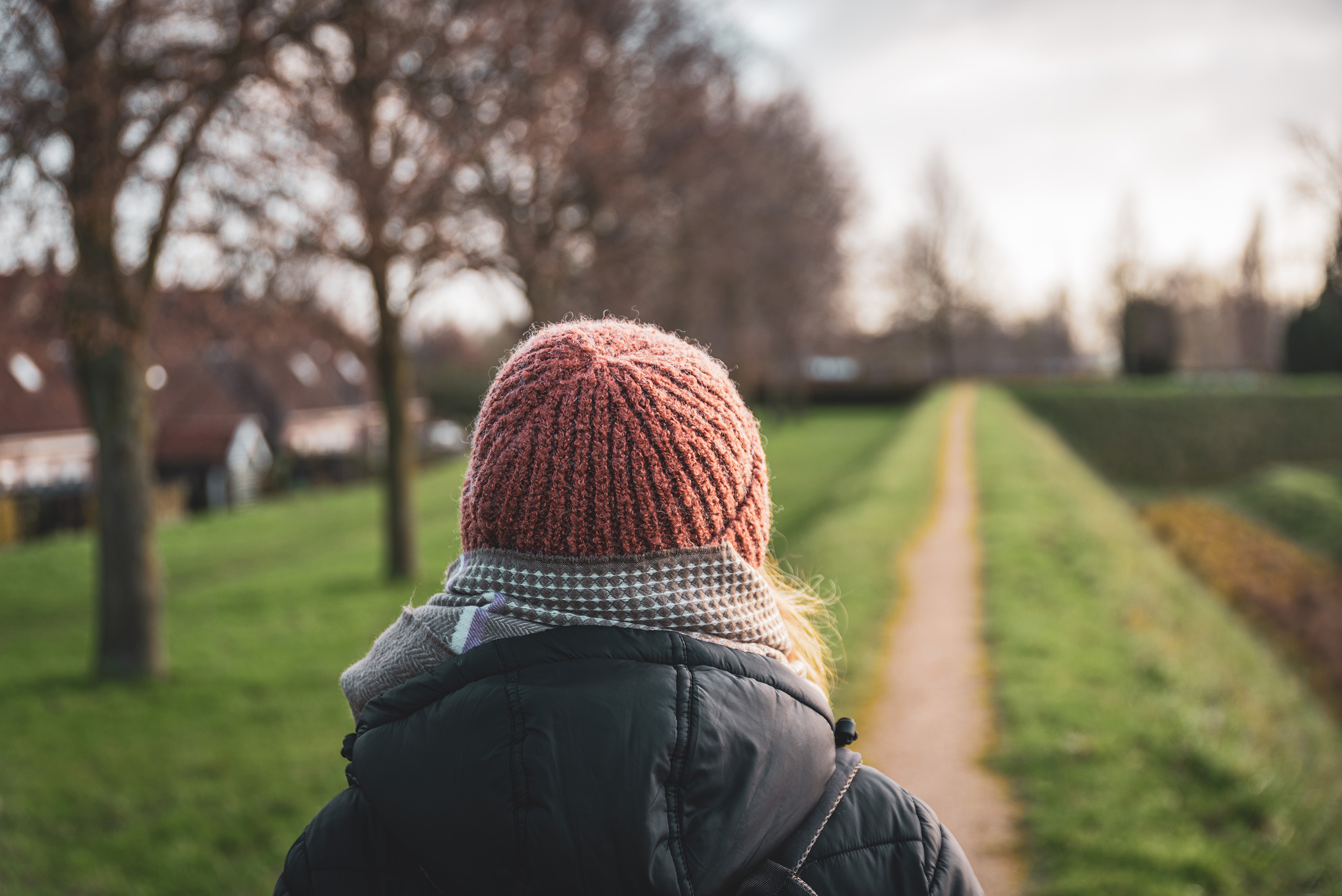 Vrouw met muts van achterkant op een wandelpad
