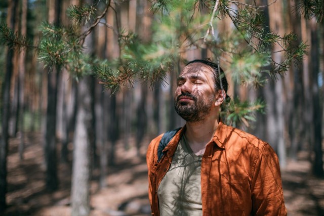 afbeelding van een man met zijn ogen dicht in het bos.
