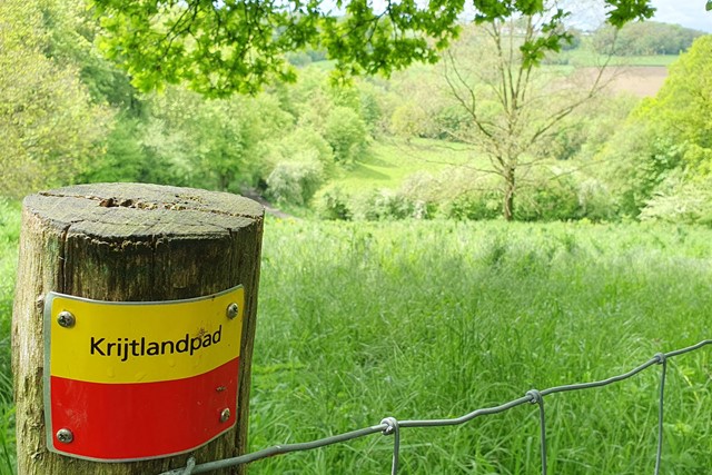 paaltje met rood-gele markering Krijtlandpad en glooiend landschap