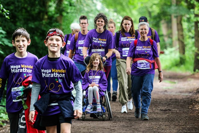 Wandelende kinderen en volwassenen, een meisje in een rolstoel, in het bos