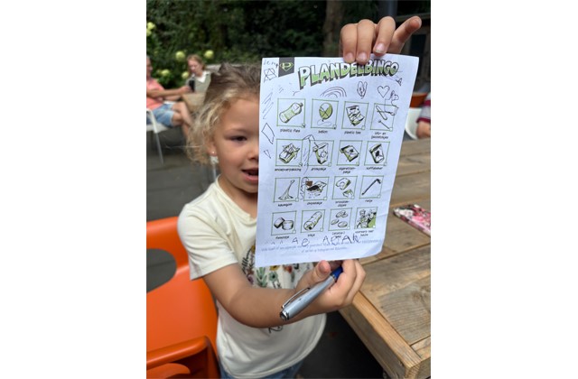 Meisje houdt blaadje met plandelbingo omhoog