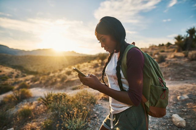 afbeelding van een wandelaar met een mobiele telefoon in haar hand.