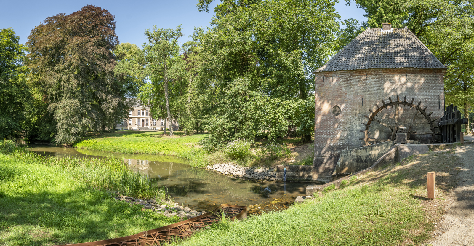 afbeelding van een landgoed met een waterrad in beeld.