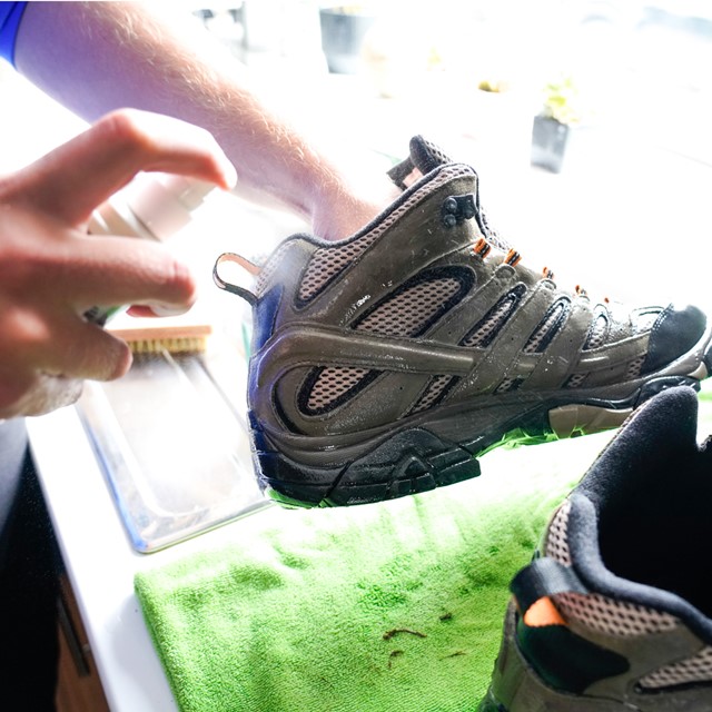 afbeelding van iemand die zijn wandelschoenen impregneert.