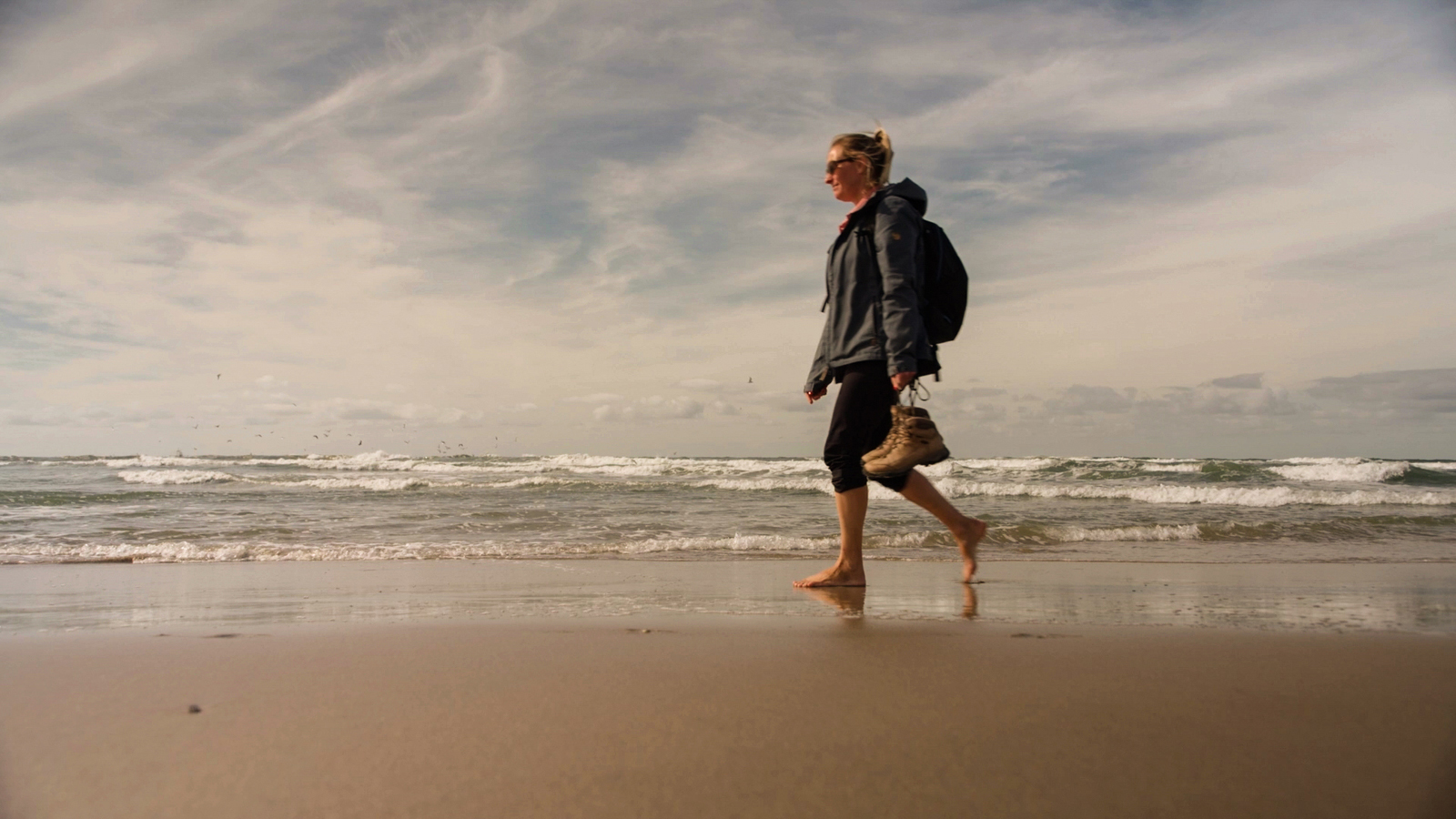 afbeelding van een vrouw die op blote voeten wandelt op het Texelse strand.