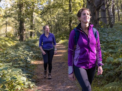 Twee sportief geklede vrouwen wandelen door het bos