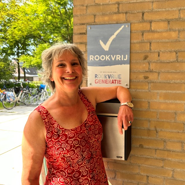 Peukenmeisje Bernadette bij een bordje 'Rookvrij'.