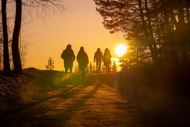 Zomerse wandeling? Smeren, smeren, smeren!; wandelaars met een ondergaande zon