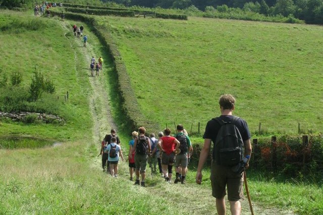 wandelaars op een heuvelachtig pad tussen de weilanden.