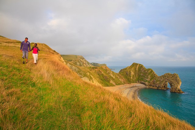 een stel wandelt langs de kust van Durdle Door, Dorset