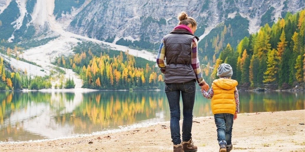 Vrouw en zoon wandelen op zand met uitzicht op het water en de bergen