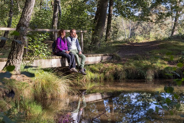 twee wandelaars zitten in de zon aan het water.