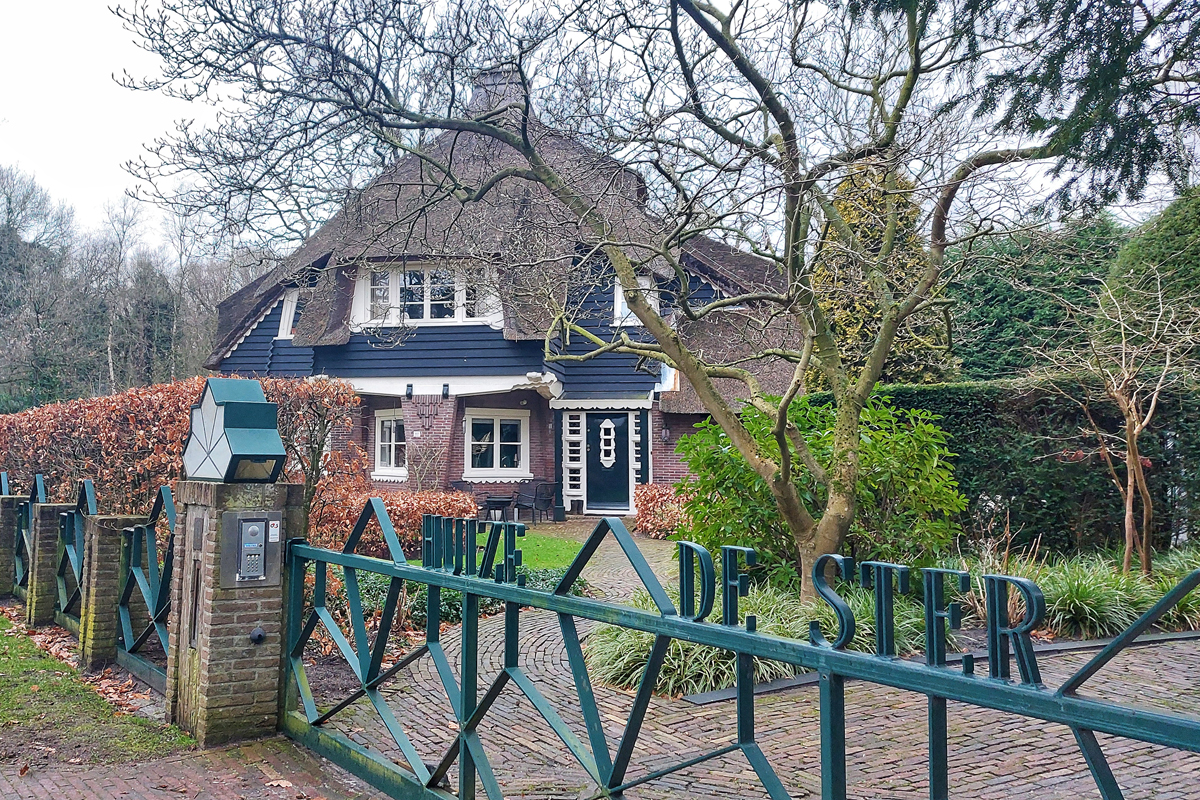 villa met rieten dak en een hek ervoor