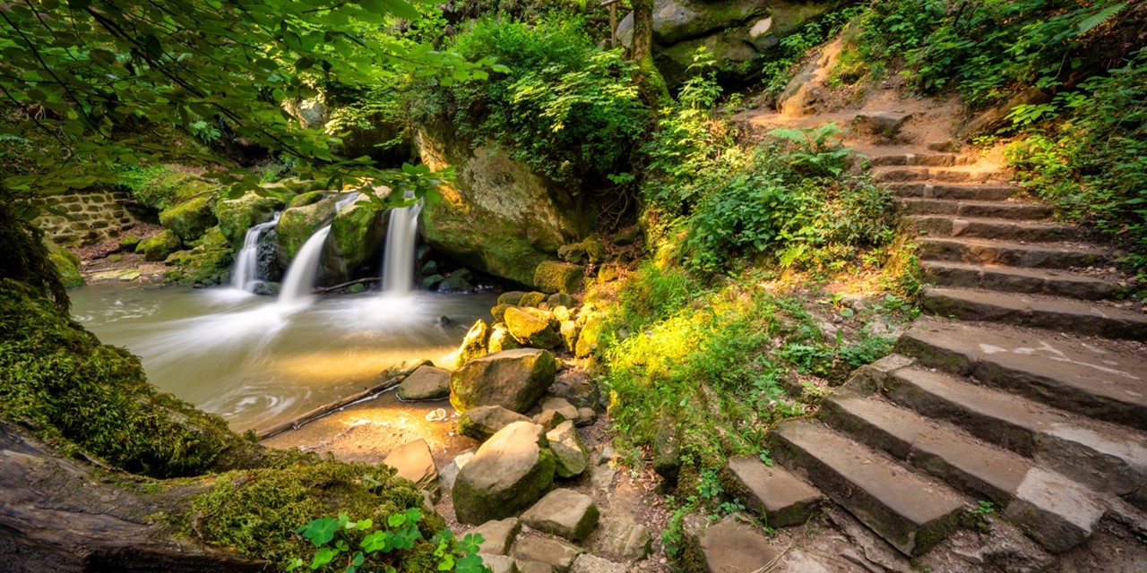 afbeelding van een waterval en trap in de Schiessentümpel in het Mullerthal.