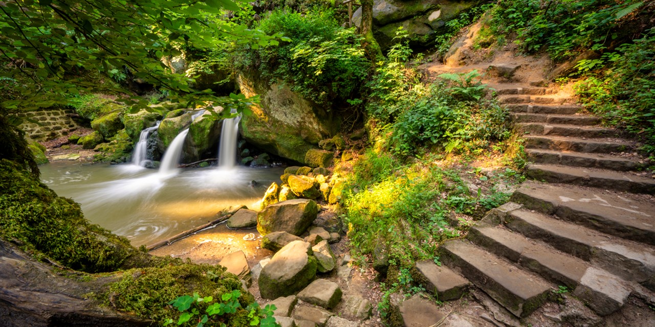 afbeelding van een waterval en trap in de Schiessentümpel in het Mullerthal.