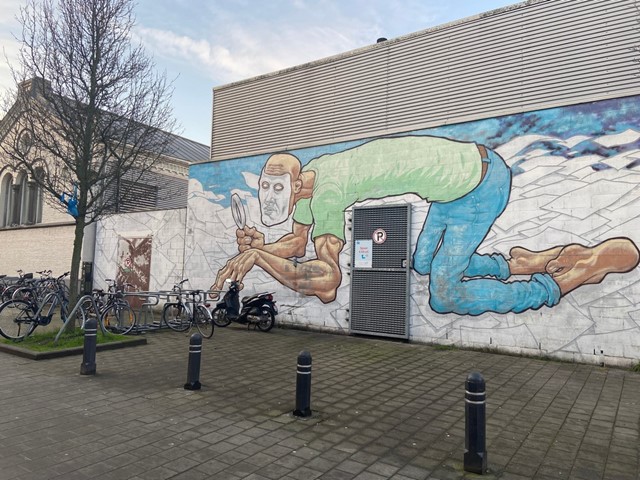 afbeelding van een muurschildering van een manfiguur met een loep.