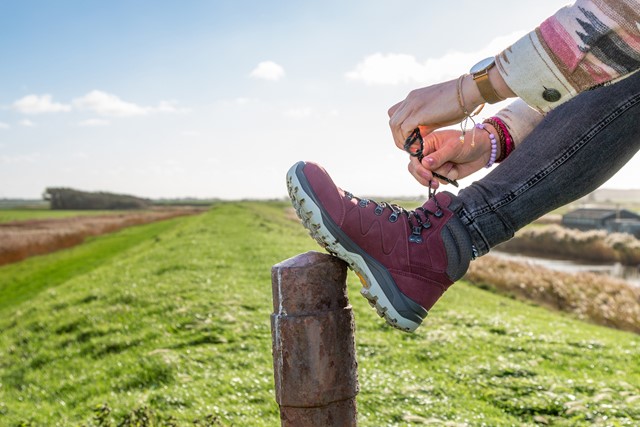 afbeelding van iemand die buiten zijn wandelschoen aantrekt.