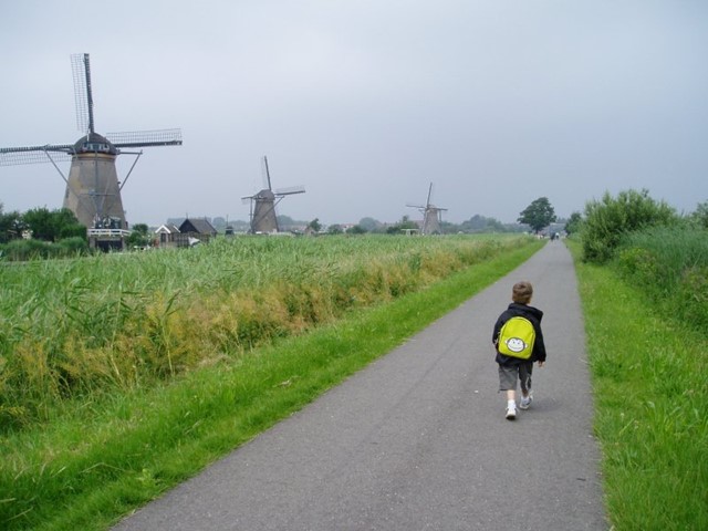 Een kind wandelt langs de molens van Kinderdijk
