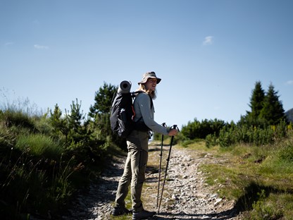 afbeelding van Rick die met een rugzak en trekkingstokken in de natuur loopt.