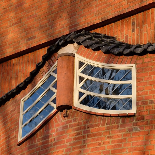 bakstenen en glooiende ramen van een gebouw in de stijl van de Amsterdamse School.
