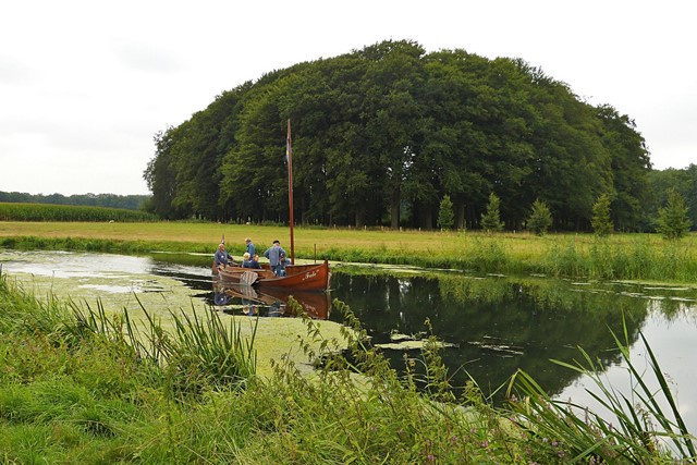 zomp op het water van de rivier de Regge, in het groene landschap met gras en bomen.