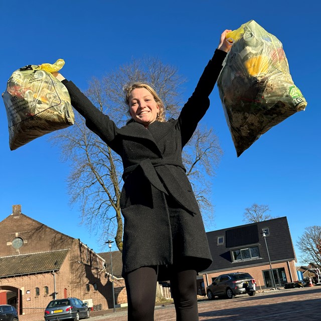 afbeelding van Annelies met twee volle vuilniszakken in haar hand.