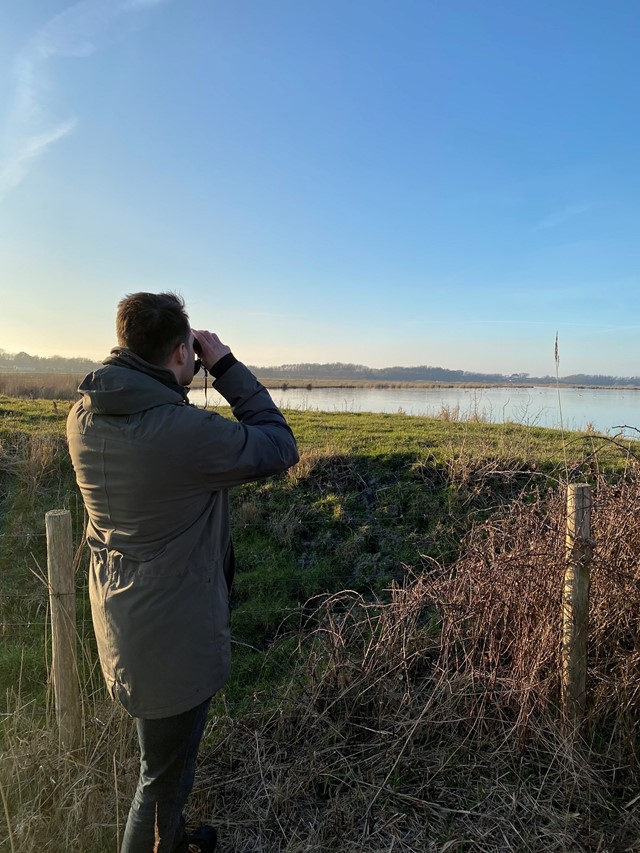 Man met verrekijker in natuur