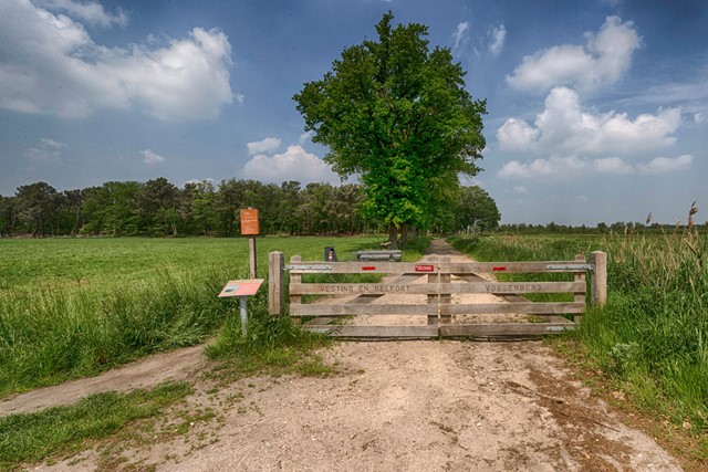 afbeelding van een hek naar het natuurgebied. 'Vesting en Belfort' en 'Vossenberg' staat erop.
