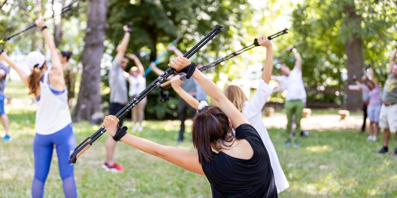 afbeelding van een groep mensen die aan het trainen zijn met Nordic Walking stokken.