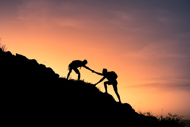 afbeelding van iemand die de ander de berg op helpt.