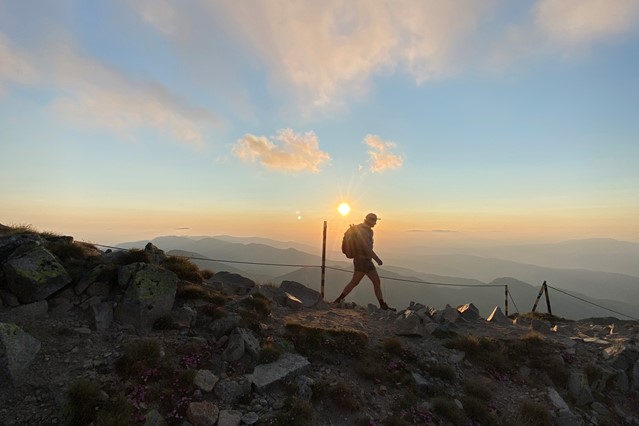 afbeelding van een hiker in de zon, in de bergen.