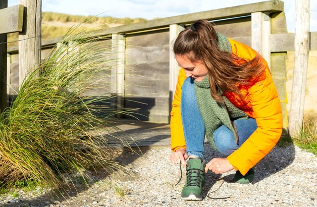 afbeelding van een vrouw die haar nieuwe wandelschoenen aandoet.