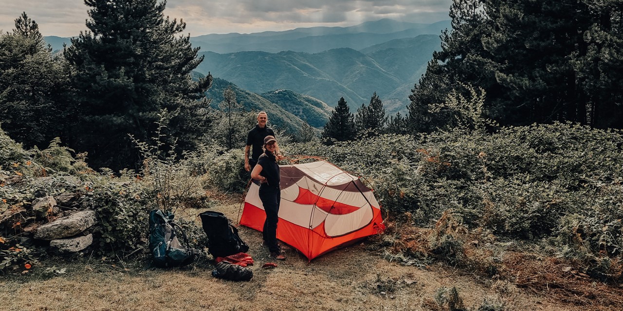 twee wandelaars zetten een tent op in de bergen.