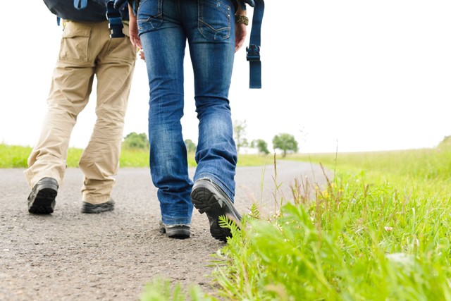 Wandelaars met lange broek en stevige schoenen op wandelpad naast gras