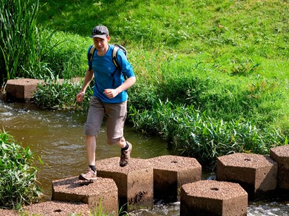 Een wandelaar steekt een riviertje over bij Hellendoorn