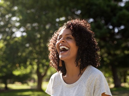 vrouw lacht terwijl ze buiten loopt.