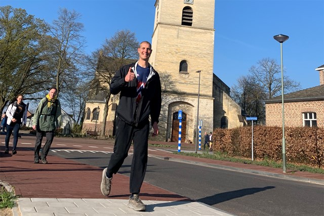 afbeelding van Maarten die wandelt op straat bij een kerk.