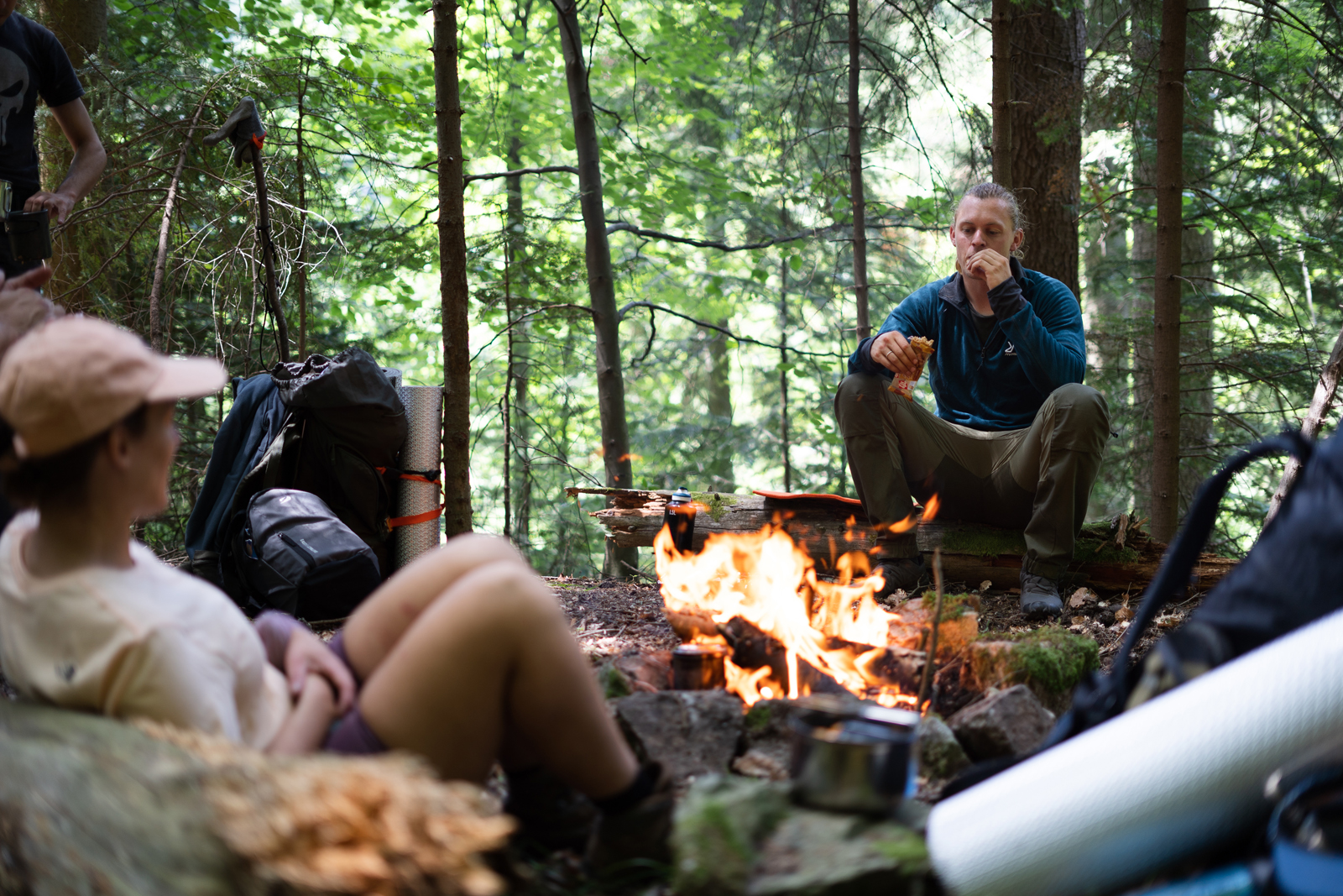 Rick eet wat bij het vuur tijdens een trektocht.