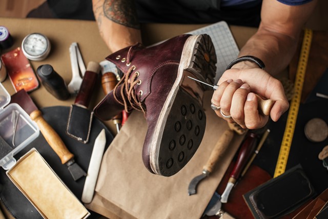 schoenmaker werkt aan de zool van een leren schoen.