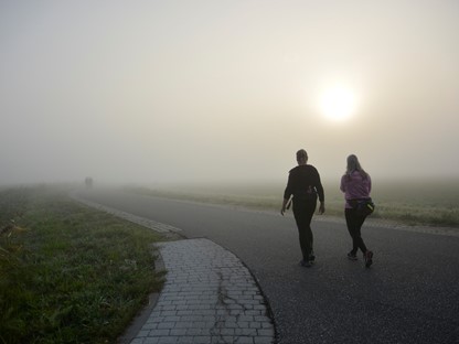 afbeelding van twee wandelaars op een pad in de mist.