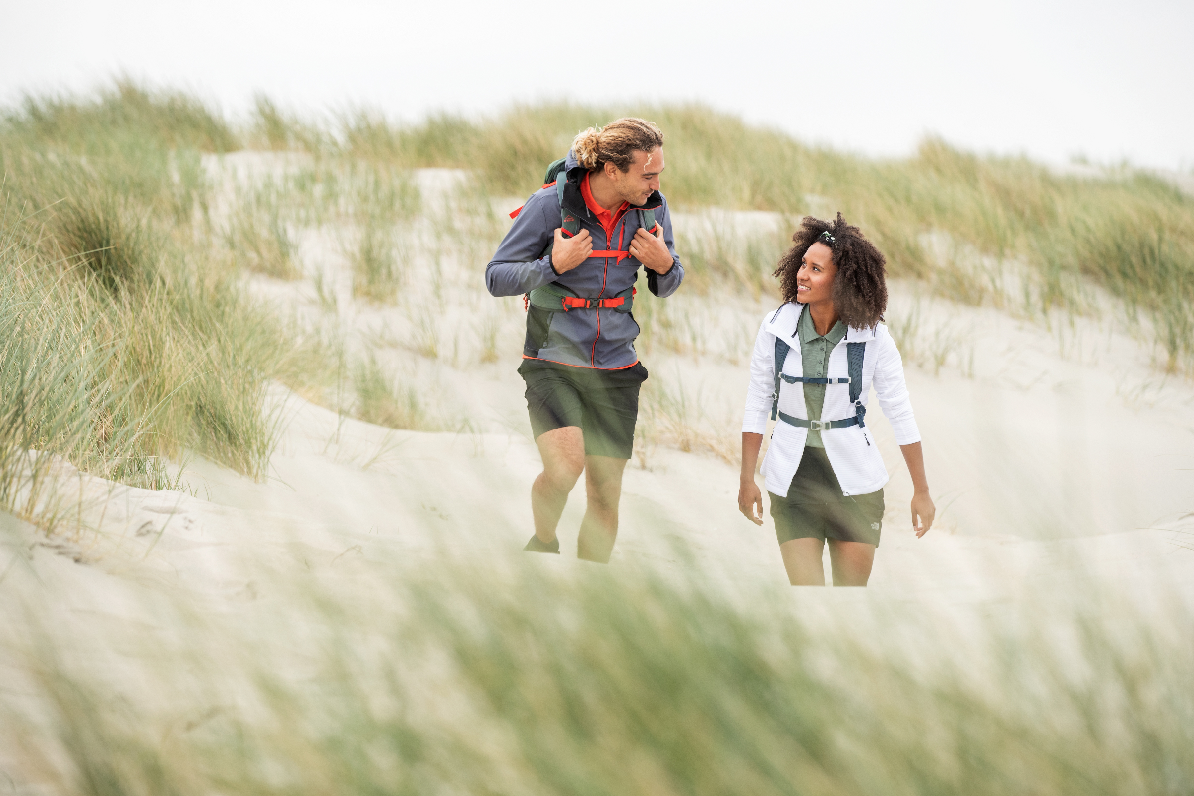 Twee personen wandelen in de duinen door het zand