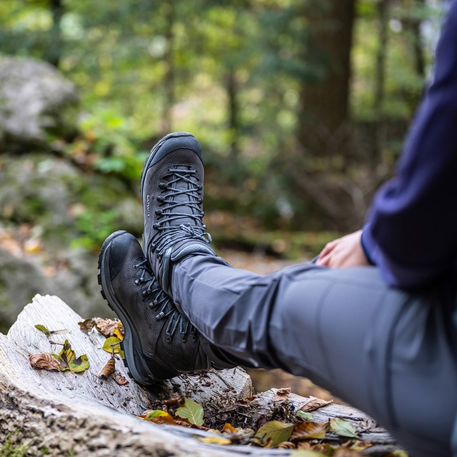 benen over elkaar met de wandelschoenen rustend op een stuk boom.