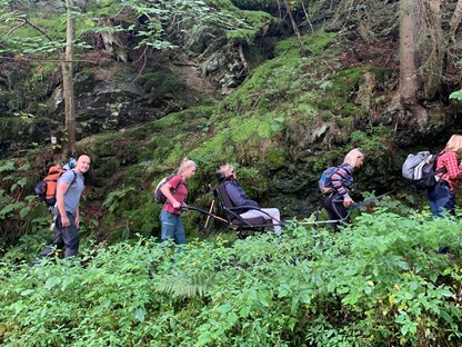 afbeeldingen van wandelaars in de natuur, met een off-road rolstoel.