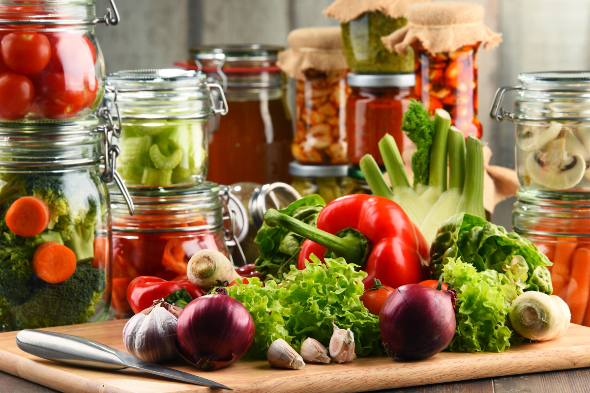 afbeelding van veel groenten op de voorgrond en weckpotten op de achtergrond.